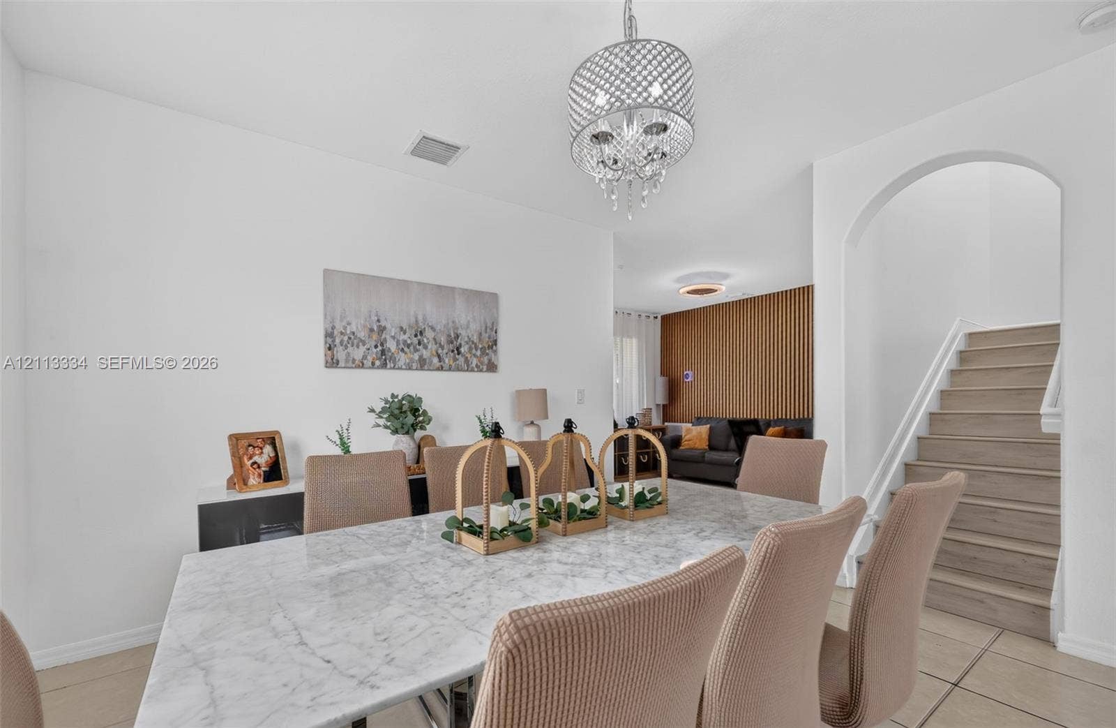 28232 SW 128th Path, Homestead, FL 33033 Dining area featuring a circular crystal chandelier, arched entryway, staircase with wood-finish treads, and vertical wood slat accent wall