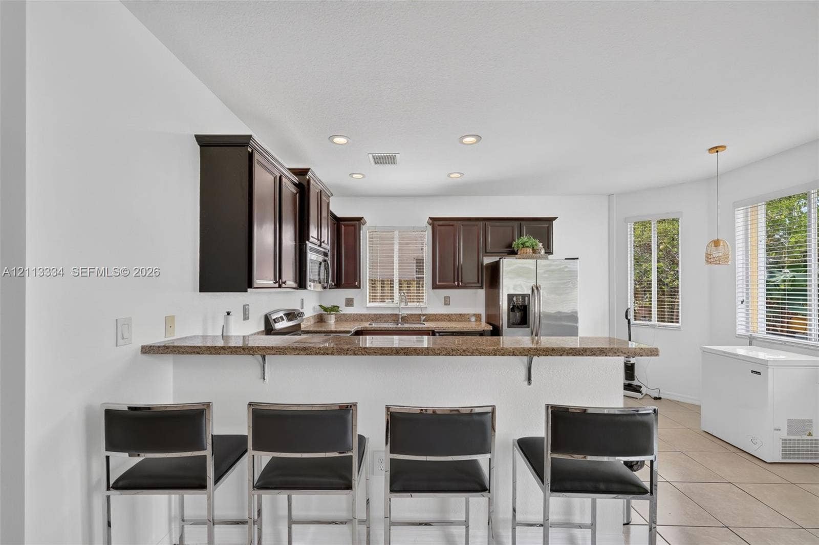 28232 SW 128th Path, Homestead, FL 33033 Kitchen featuring dark-toned cabinetry, stone-finish countertops, a breakfast bar, recessed lighting, and tile flooring