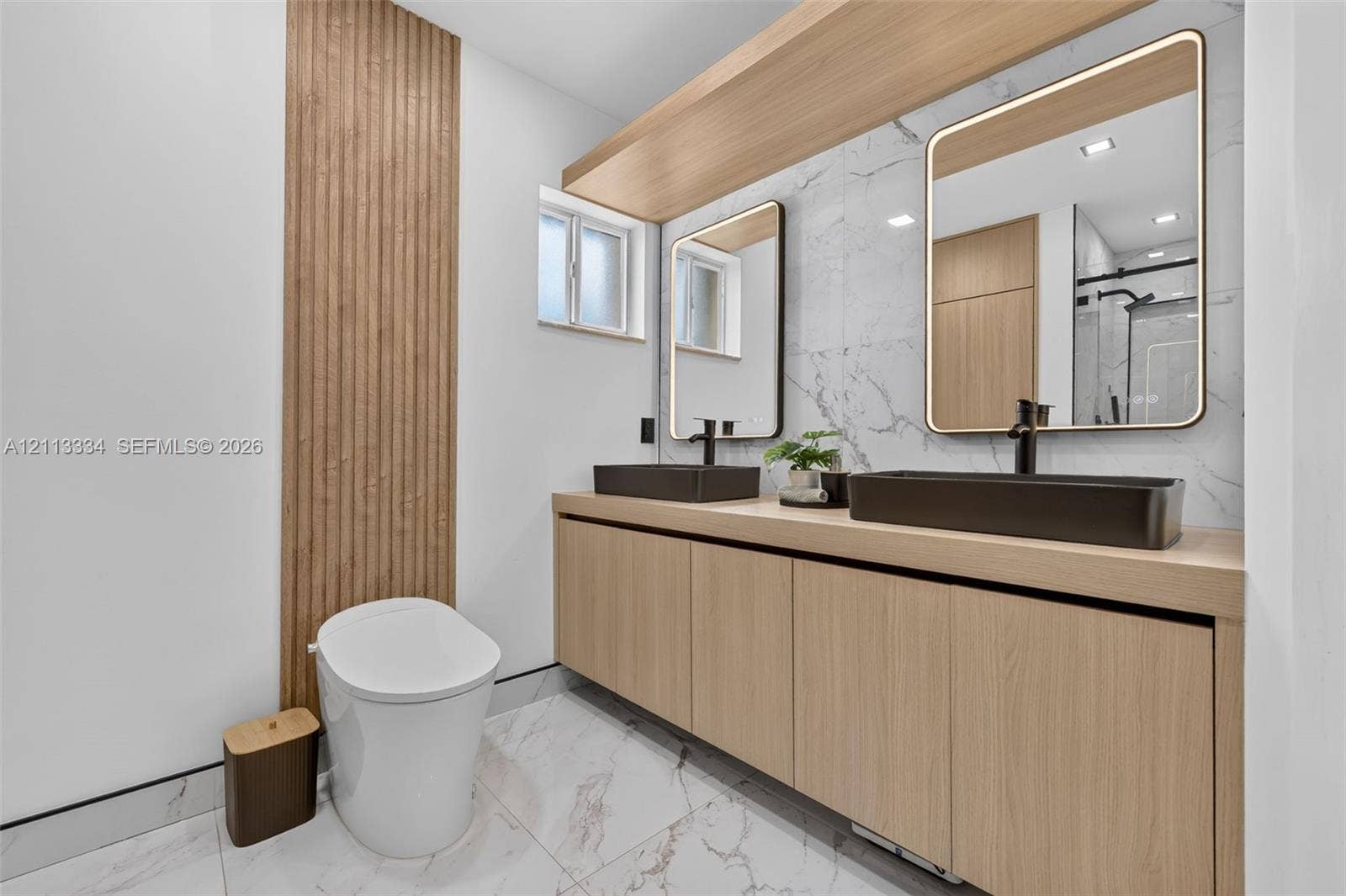 28232 SW 128th Path, Homestead, FL 33033 Floating vanity featuring wood-finish cabinetry, dual rectangular vessel sinks, matte black faucets, integrated LED-lit mirrors, and floor-to-ceiling wood slat wall detailing