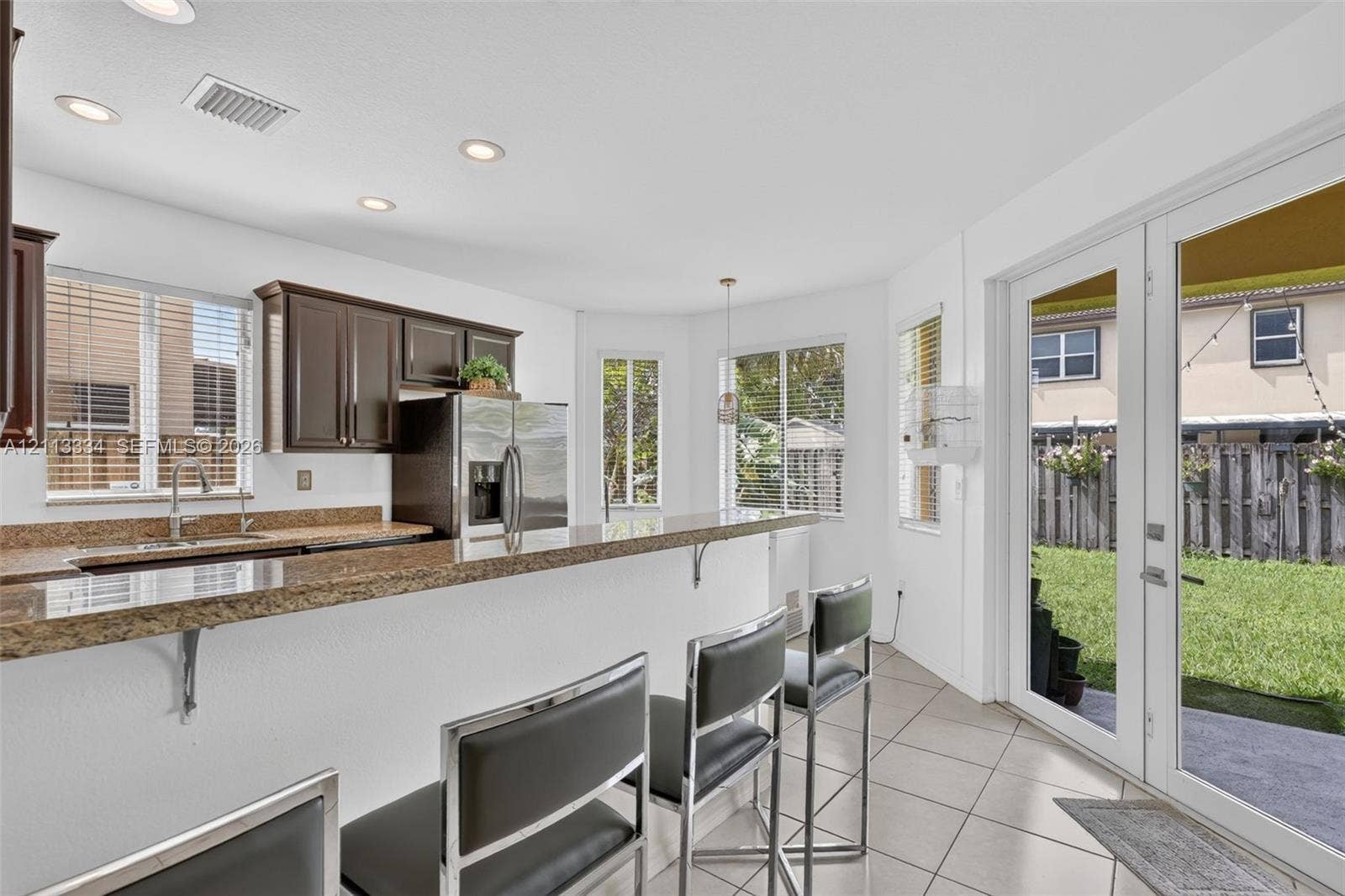 28232 SW 128th Path, Homestead, FL 33033 Kitchen featuring stone countertops, dark wood cabinetry, recessed lighting, tile flooring, and glass-paneled double doors providing rear exterior access