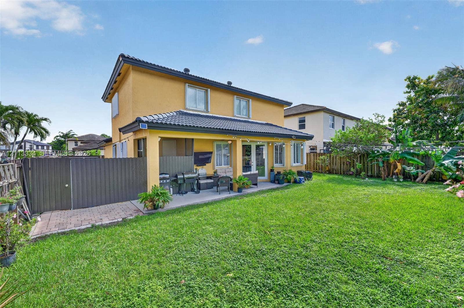 28232 SW 128th Path, Homestead, FL 33033 Two-story exterior with a tiled roof, a covered concrete patio, and a fenced backyard