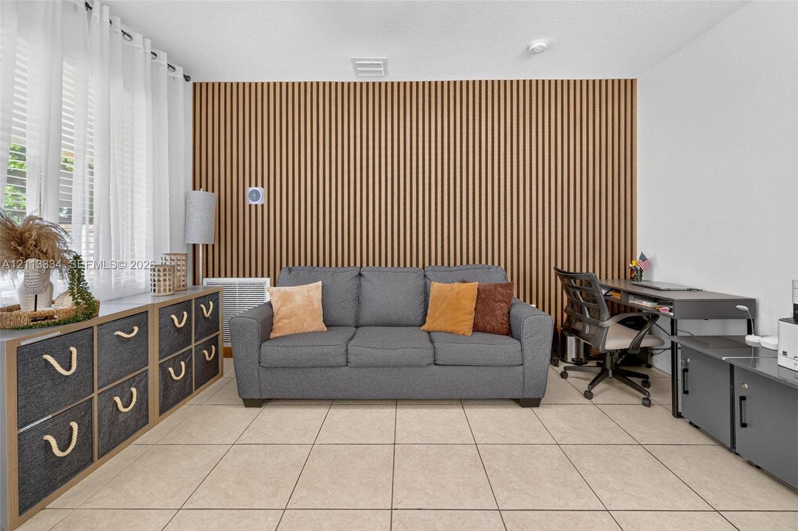 28232 SW 128th Path, Homestead, FL 33033 Vertical wood-slat accent wall featuring a linear texture, complemented by neutral tile flooring and large windows with integrated curtain hardware