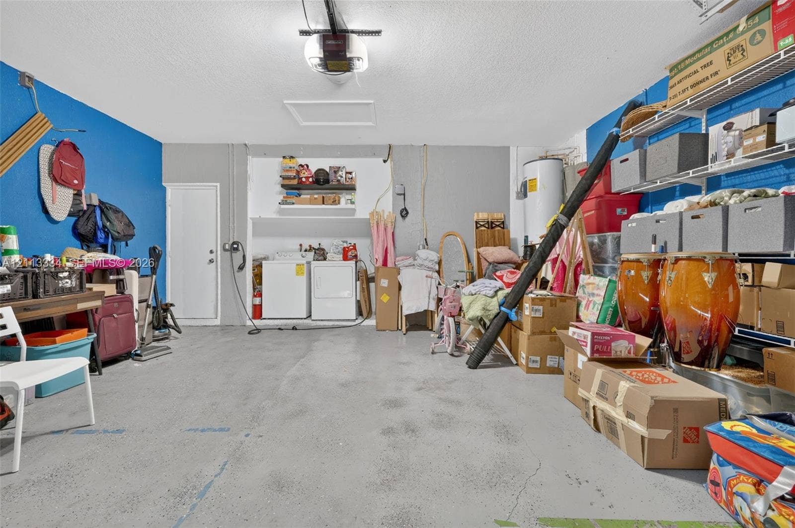 28232 SW 128th Path, Homestead, FL 33033 Garage interior featuring concrete flooring, an overhead door opener, a dedicated laundry area, and integrated metal shelving