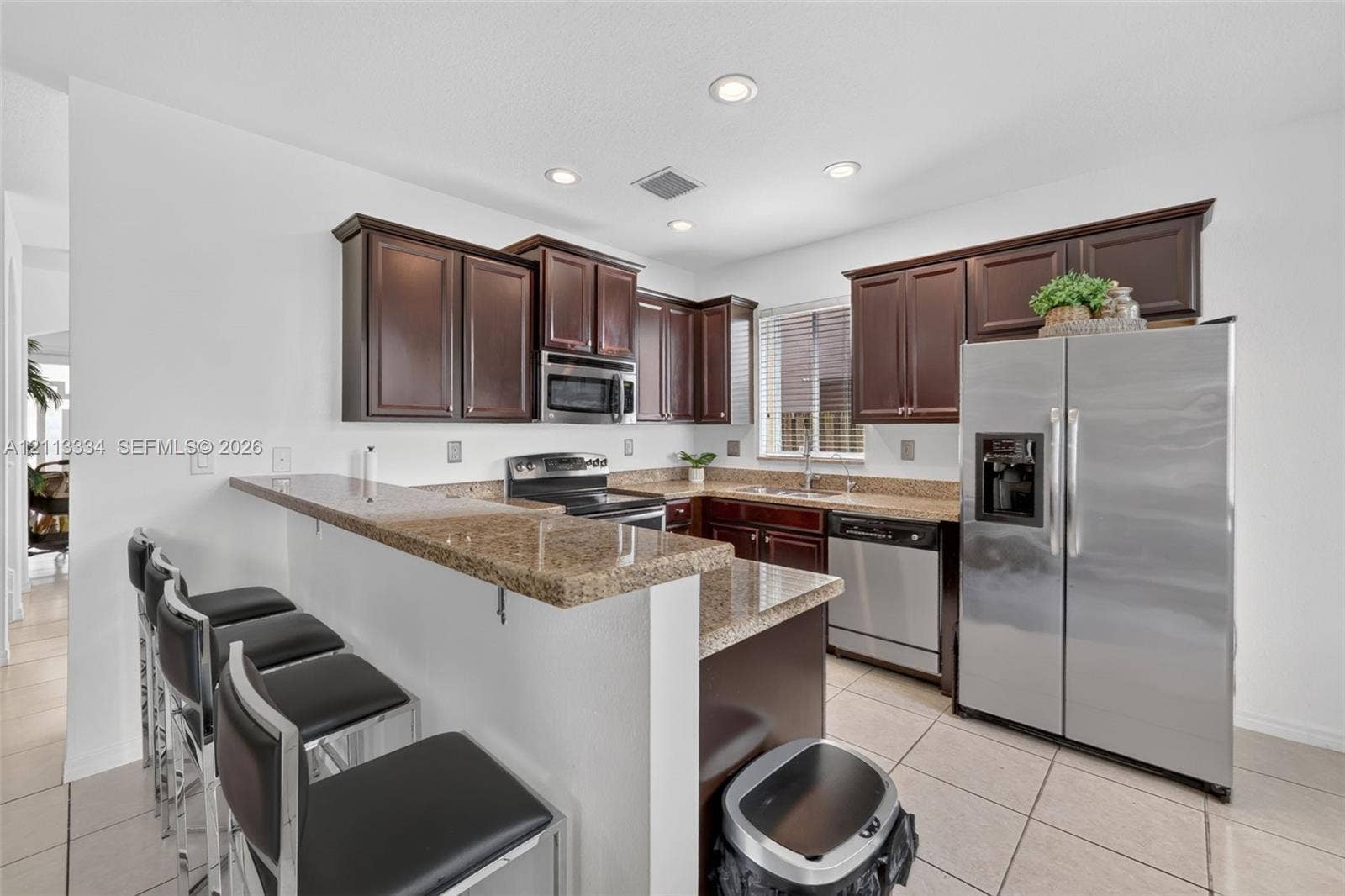 28232 SW 128th Path, Homestead, FL 33033 Kitchen featuring dark wood cabinetry, stone-surface countertops, breakfast bar, recessed lighting, and stainless steel appliances