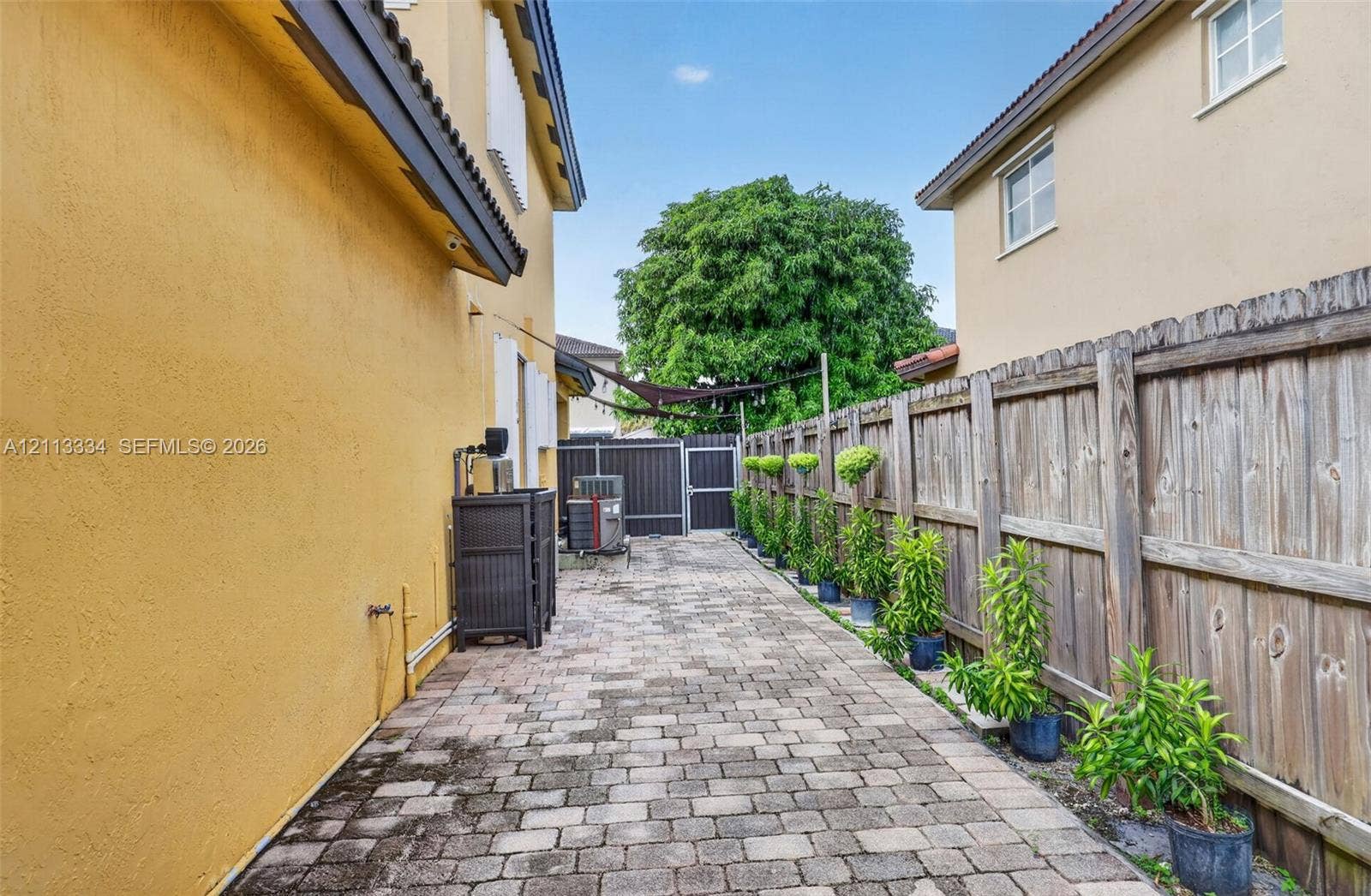 28232 SW 128th Path, Homestead, FL 33033 Side yard featuring paver patio, wood privacy fencing, and structured landscaping