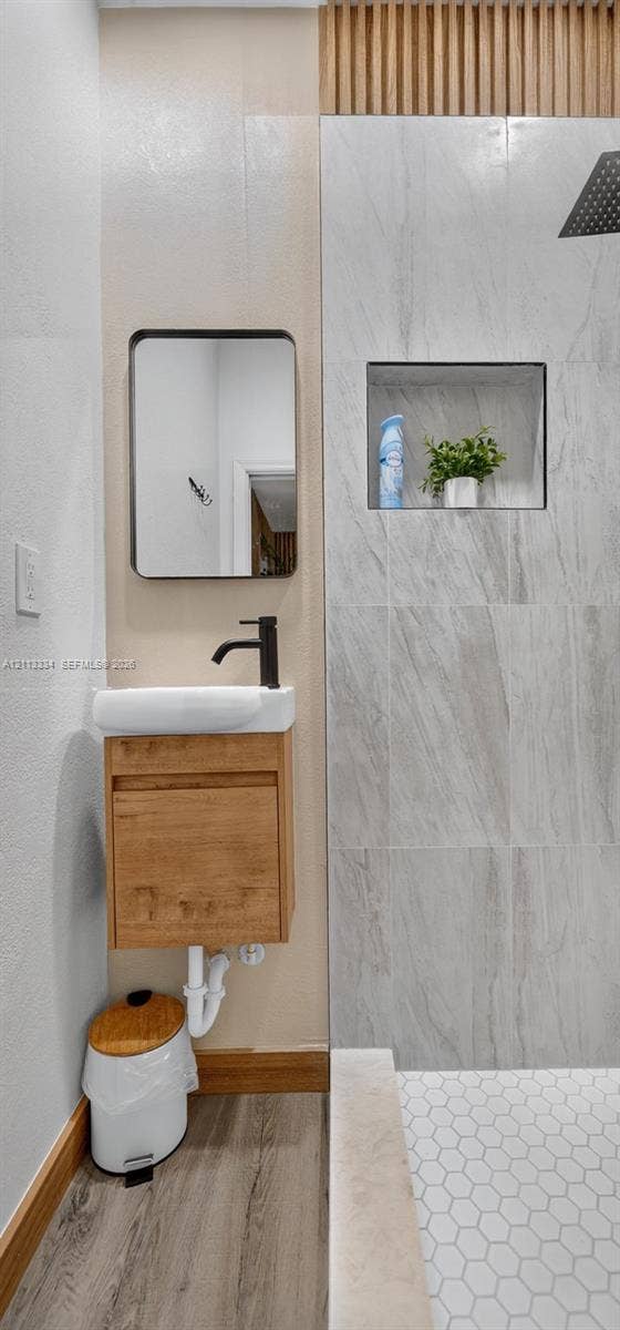 28232 SW 128th Path, Homestead, FL 33033 Wall-mounted wood-finish vanity with a rectangular sink, matte black faucet, rectangular mirror with a black frame, floor-to-ceiling stone-look wall tiling, and hexagonal floor tiles