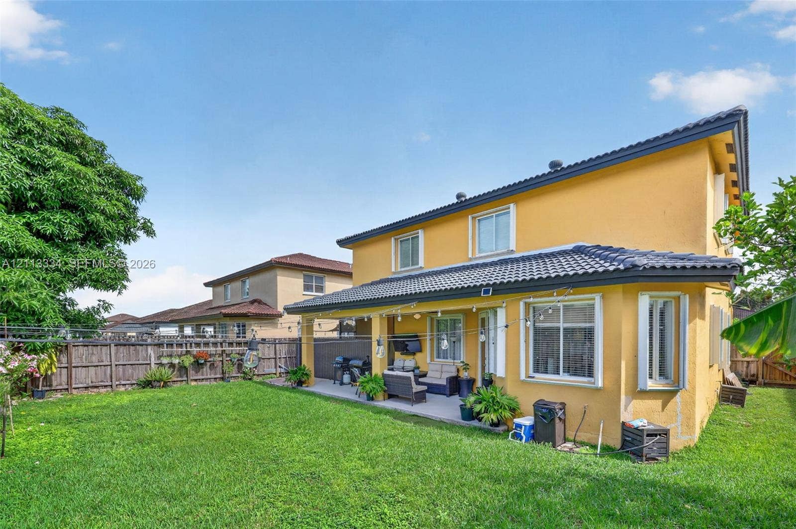 28232 SW 128th Path, Homestead, FL 33033 Stucco exterior residence featuring a covered concrete patio, tile roof, and a fenced backyard with lawn