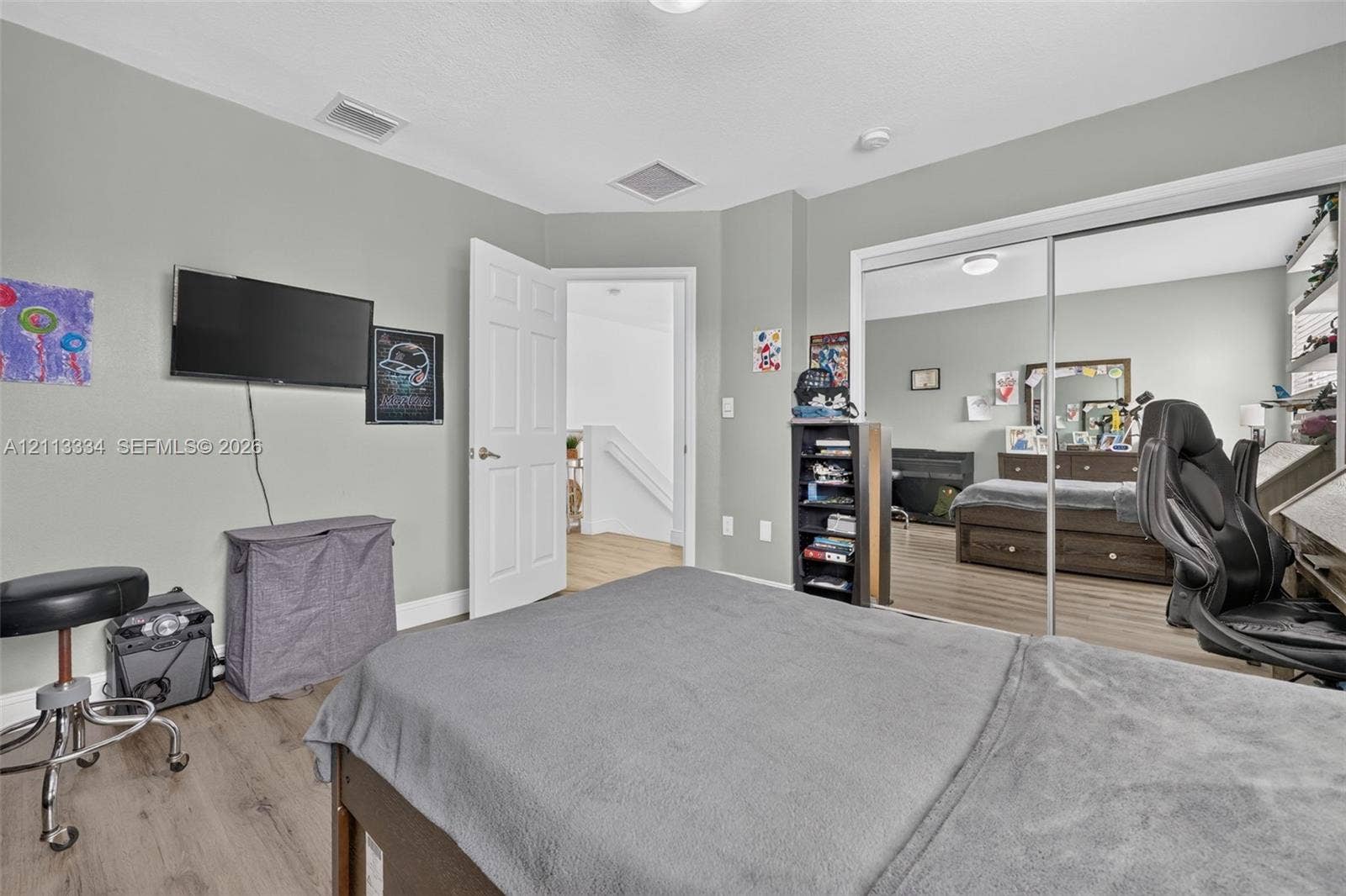 28232 SW 128th Path, Homestead, FL 33033 Room interior featuring wood-finish flooring, a double-panel sliding mirrored closet door, and a multi-panel interior swing door