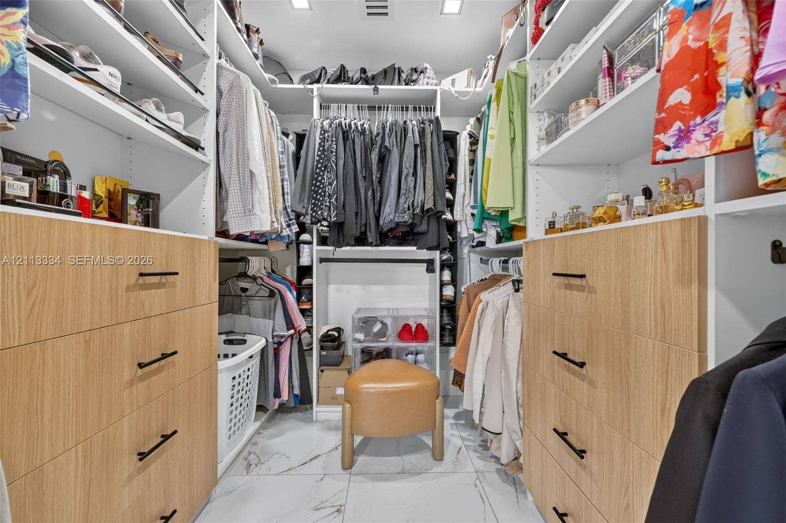 28232 SW 128th Path, Homestead, FL 33033 Custom walk-in closet featuring white built-in shelving, wood-finish cabinetry, matte black hardware, and stone-finish flooring