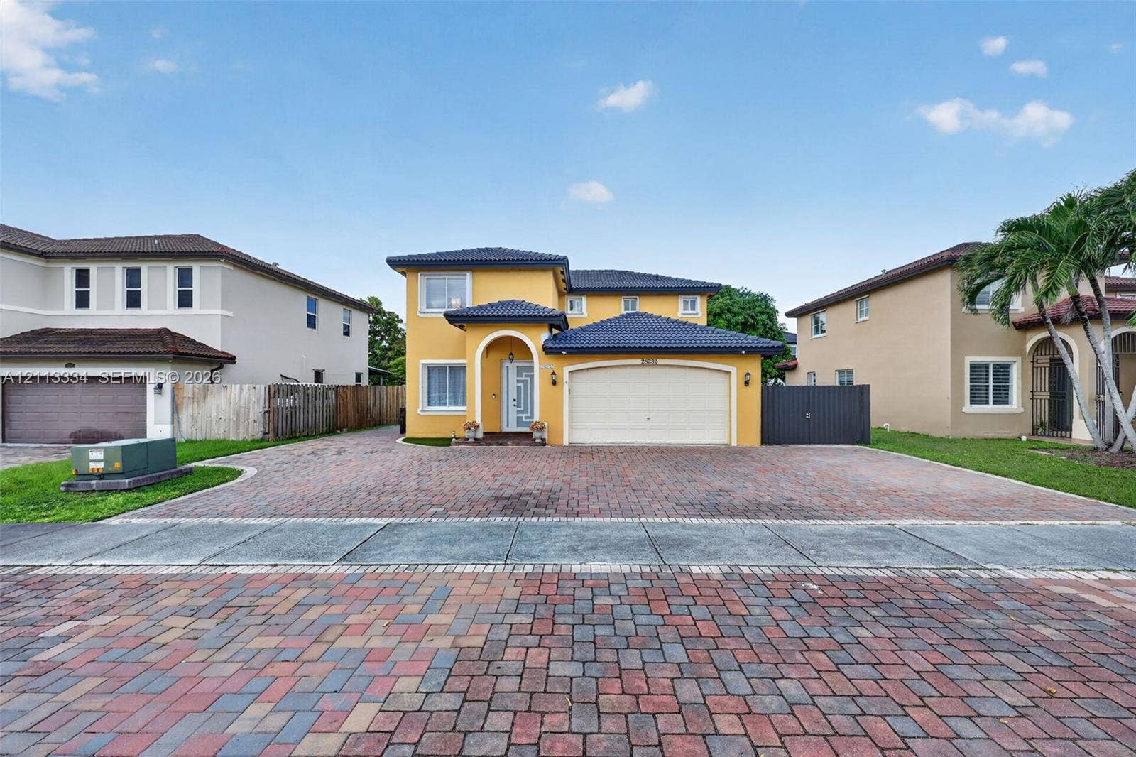 28232 SW 128th Path, Homestead, FL 33033 Two-story residence featuring a tile roof, stucco exterior, arched entryway, and a multi-car garage with a paver driveway