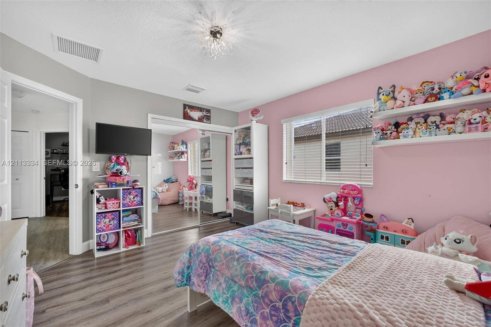 28232 SW 128th Path, Homestead, FL 33033 Bedroom featuring wood-finish flooring, mirrored sliding closet doors, a horizontal window with blinds, and an architectural starburst flush-mount ceiling light