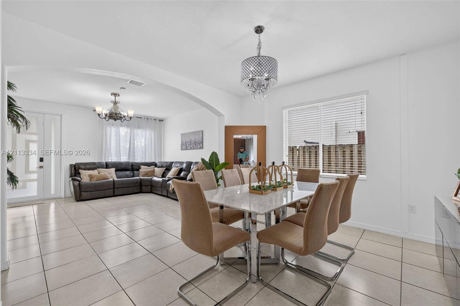 28232 SW 128th Path, Homestead, FL 33033 Open-concept interior featuring large-format ceramic tile flooring, arched architectural detailing, and two decorative crystal-style chandeliers