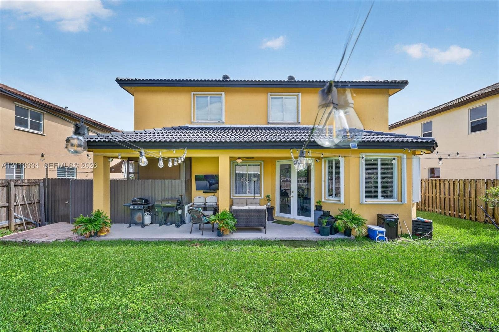 28232 SW 128th Path, Homestead, FL 33033 Rear exterior featuring a covered patio, tile roof, and enclosed backyard with wood-style fencing
