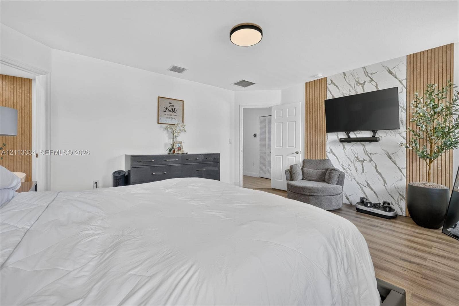 28232 SW 128th Path, Homestead, FL 33033 Wood-finish flooring, accent wall featuring vertical wood slat detailing, stone-finish paneling, and a flush-mount circular ceiling light fixture