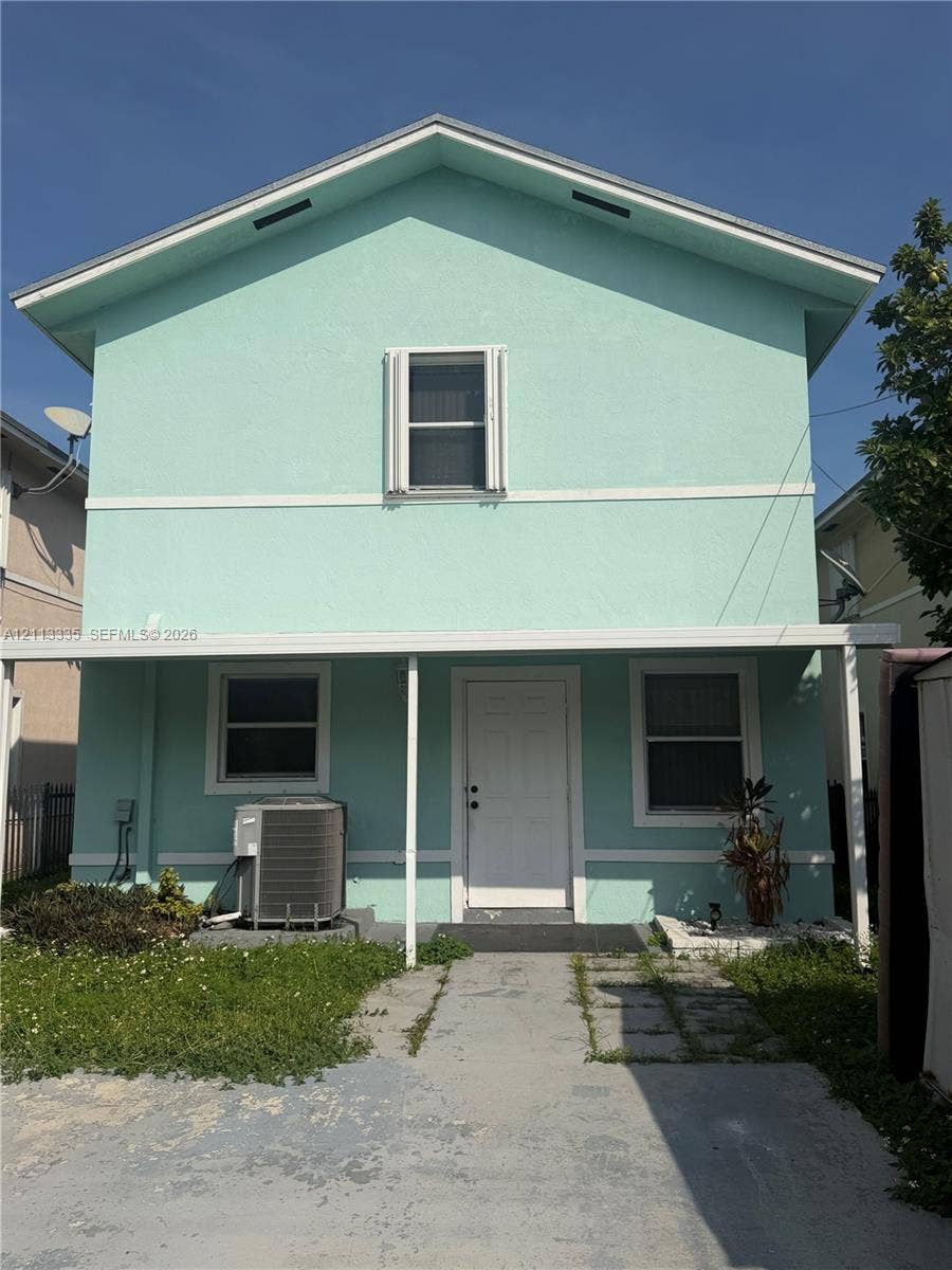 1990 NW 1st Place, Miami, FL 33136 Two-story exterior featuring a gabled roof, stucco finish, covered front porch, and concrete driveway