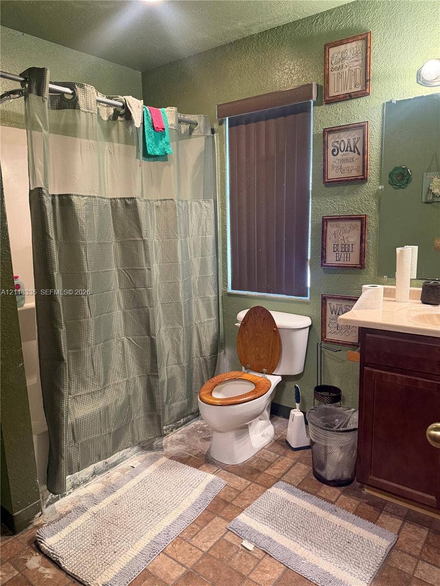 1990 NW 1st Place, Miami, FL 33136 Bathroom featuring a shower-tub combination, wall-mounted vanity with a solid-surface countertop, and ceramic tile flooring
