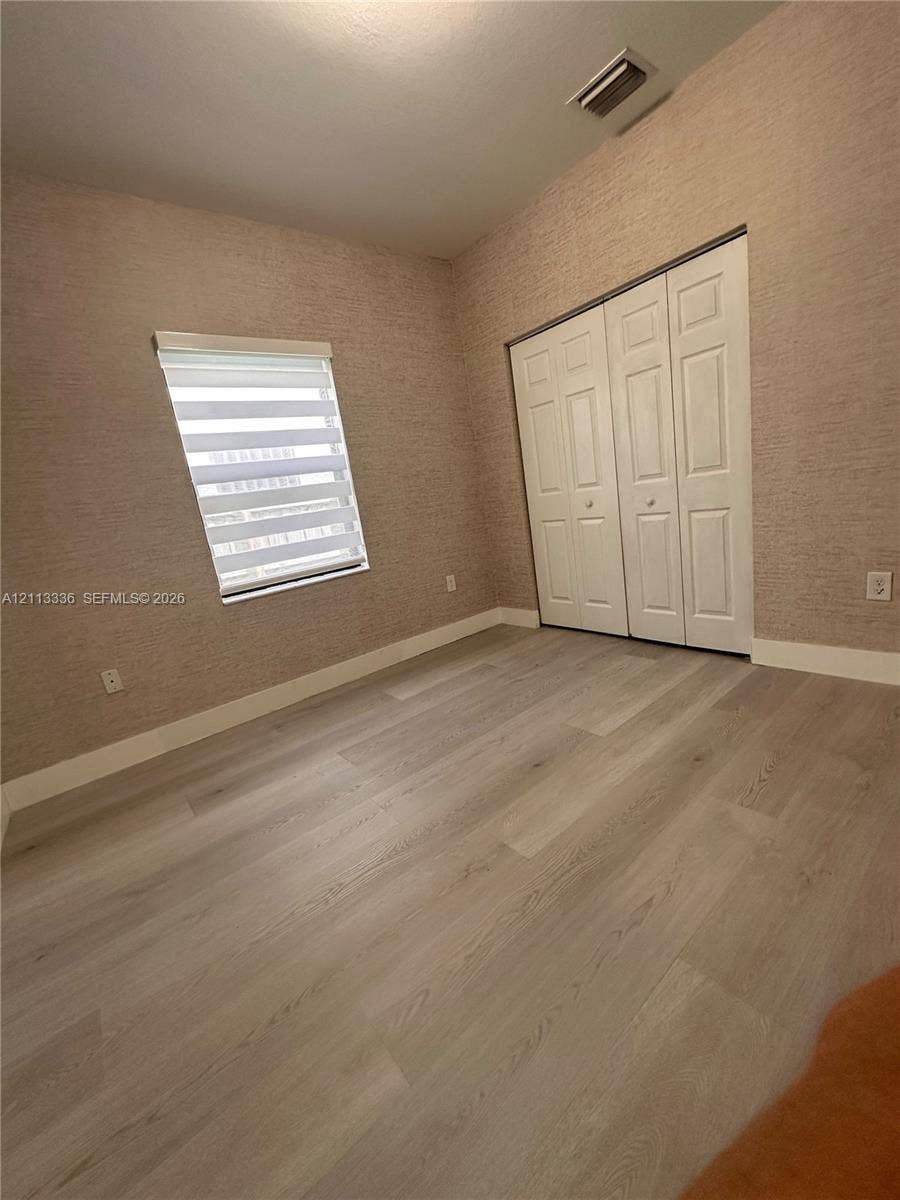 Room featuring textured wall coverings, wood-finish flooring, and a multi-panel closet door
