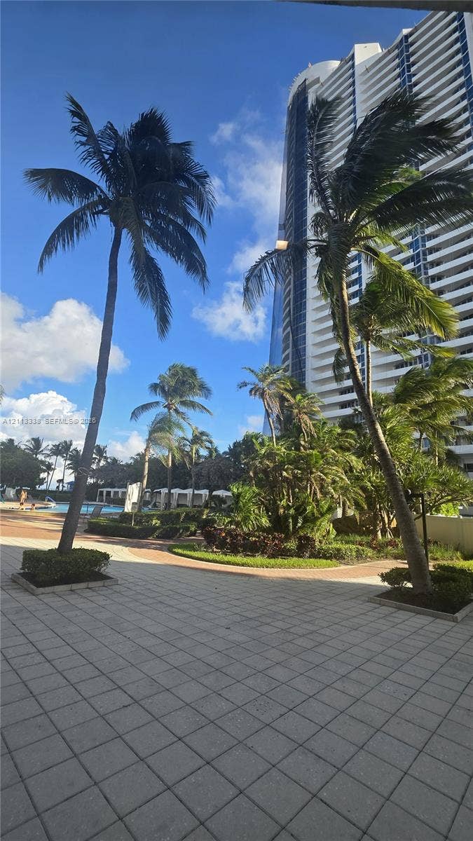 3001 S Ocean Drive, #1539, Hollywood, Hollywood, FL 33019 High-rise building exterior featuring tiered balconies, paved terrace, mature palm trees, and manicured landscaping