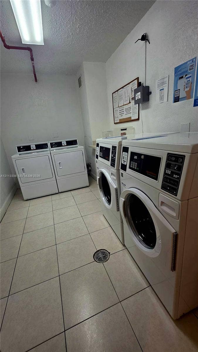 3001 S Ocean Drive, #1539, Hollywood, Hollywood, FL 33019 Laundry facility equipped with four commercial-grade front-load washers and dryers, white-toned ceramic tile flooring, and integrated ceiling lighting