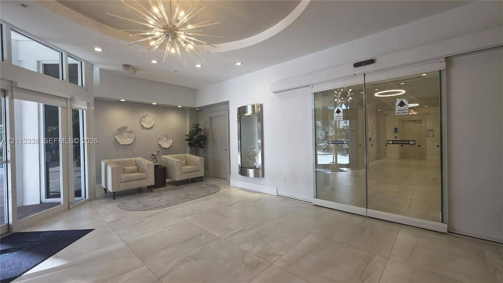 3001 S Ocean Drive, #1539, Hollywood, Hollywood, FL 33019 Entrance lobby featuring large-format tile flooring, a recessed circular ceiling detail, a geometric starburst chandelier, integrated recessed lighting, and a wall-mounted metal water feature