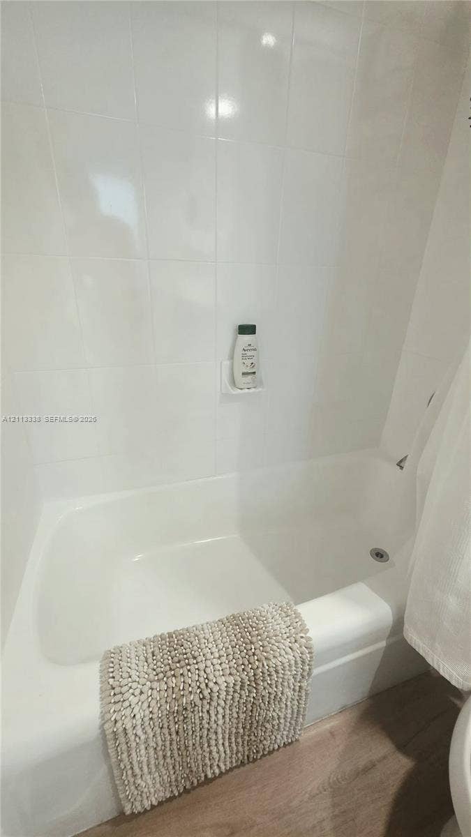 3001 S Ocean Drive, #1539, Hollywood, Hollywood, FL 33019 Bathtub with integrated shower, white wall tile surround, built-in soap niche, and wood-finish flooring