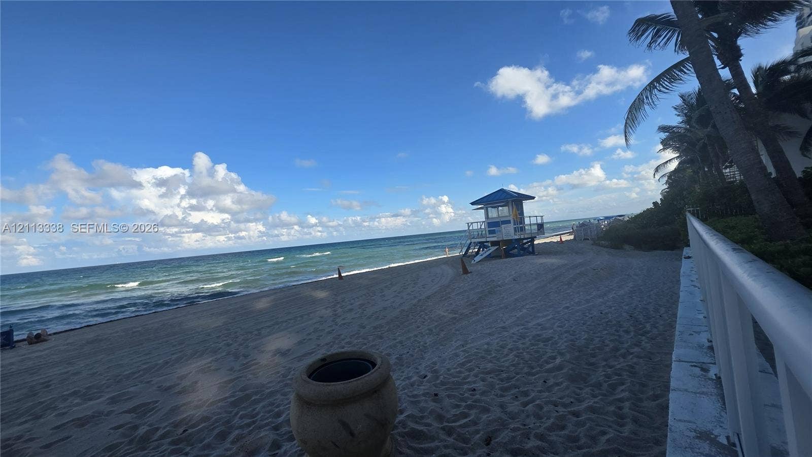 3001 S Ocean Drive, #1539, Hollywood, Hollywood, FL 33019 Sandy beachfront property featuring a white metal perimeter railing, mature palm trees, and coastal ocean scenery