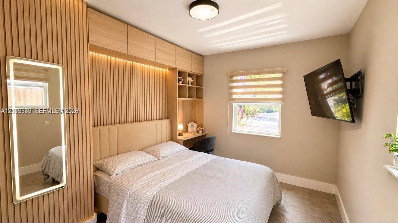 2425 SW 21st Terrace, #1, Miami, Miami, FL 33145 Slatted wood wall paneling with integrated accent lighting, custom built-in cabinetry featuring shelving and a desk surface, neutral wall finishes, and an illuminated rectangular wall mirror