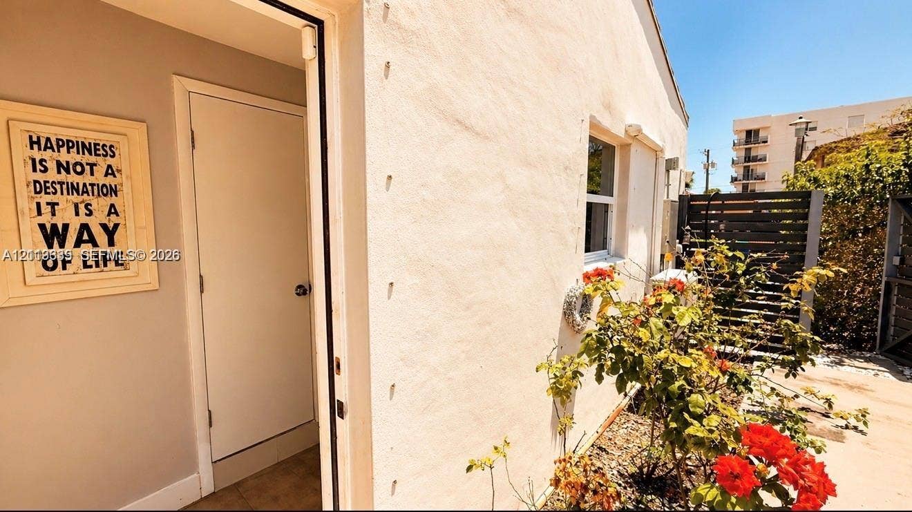 2425 SW 21st Terrace, #1, Miami, Miami, FL 33145 Stucco exterior featuring a white door, single-pane window, and horizontal slatted privacy fencing