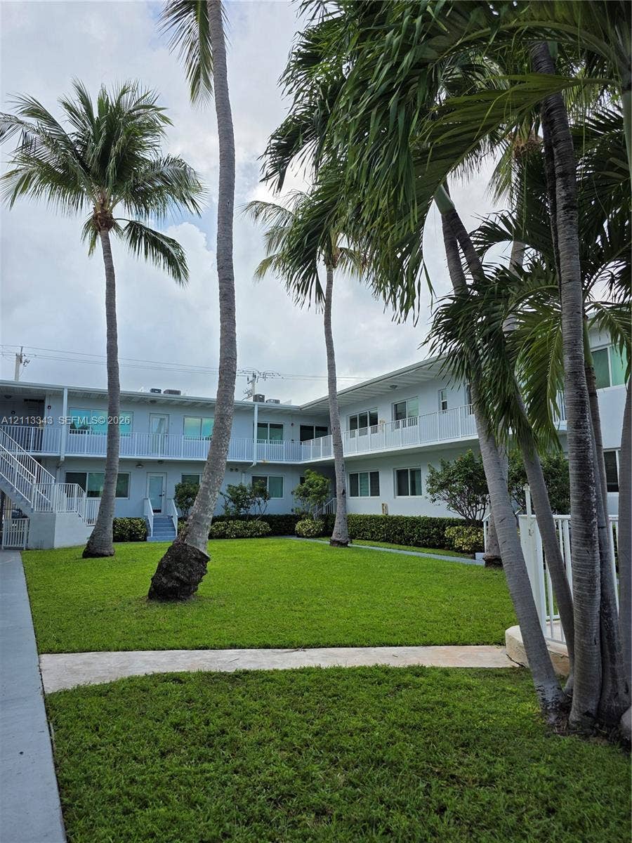 7207 Bay Drive, #2, Miami Beach, Miami Beach, FL 33141 Courtyard featuring a manicured lawn, established palm trees, concrete walkways, and perimeter shrubbery
