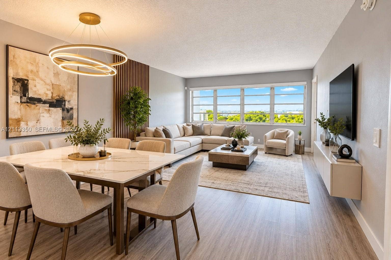 AI RENDERING-Open-concept living space featuring wood-finish flooring, a wall-mounted floating media console, a floor-to-ceiling vertical slat accent wall, and a contemporary multi-ring pendant chandelier