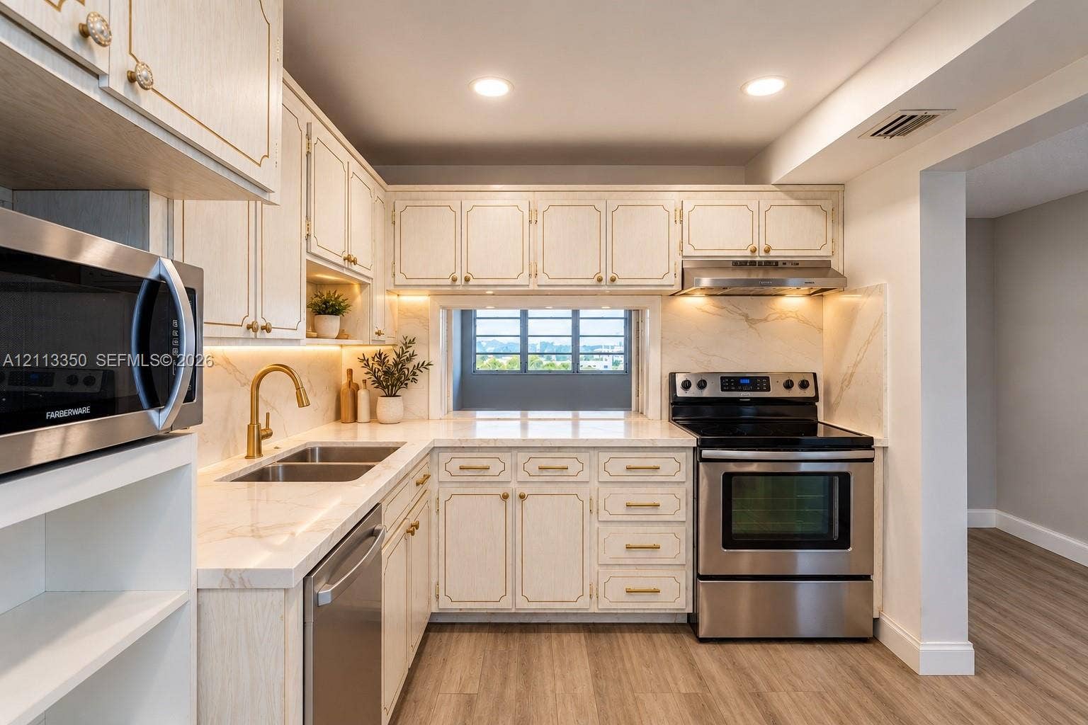 AI RENDERING-Kitchen featuring off-white cabinetry with gold-tone hardware, stone-finish countertops, stainless steel appliances, and integrated under-cabinet lighting