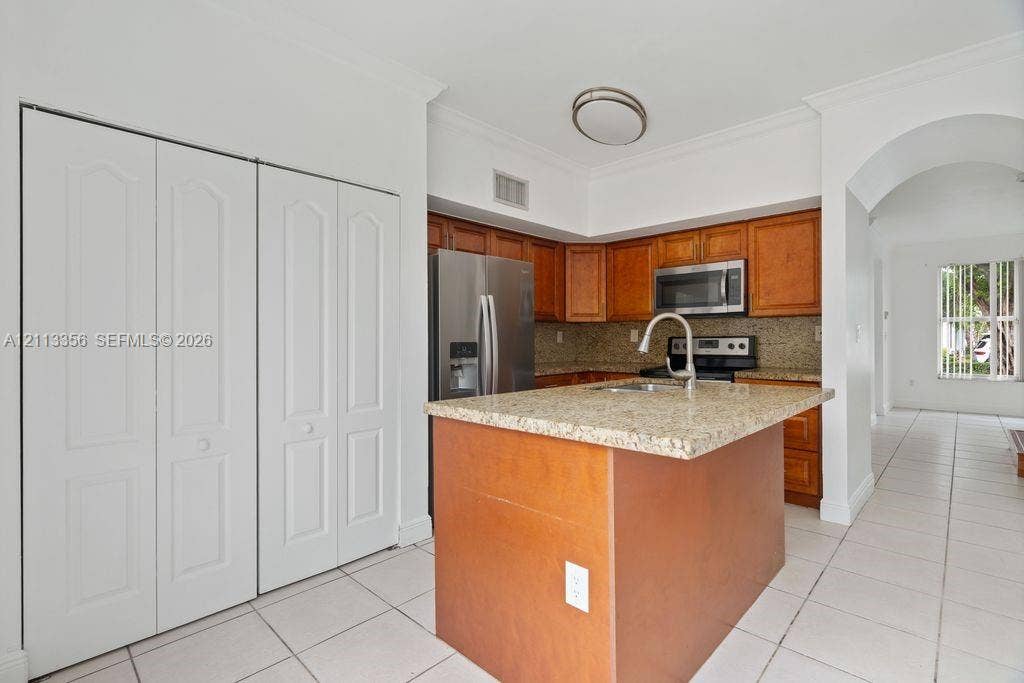 8715 SW 152nd Avenue, #312, Miami, Miami, FL 33193 Kitchen featuring wood cabinetry, stone countertops, stainless steel appliances, a center island with an integrated sink, and tile flooring
