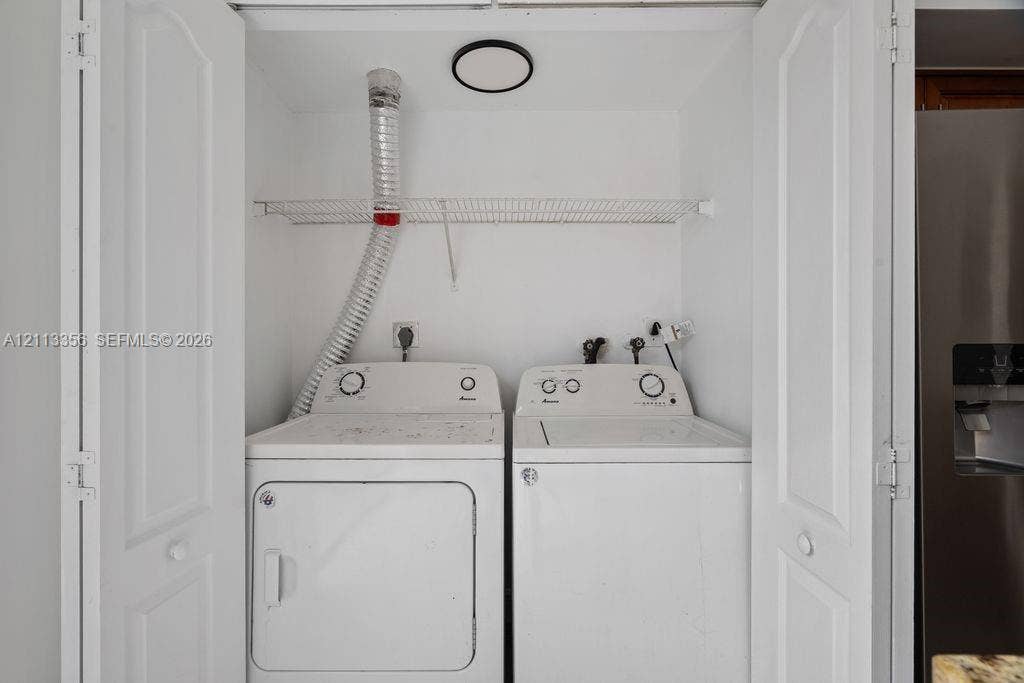 8715 SW 152nd Avenue, #312, Miami, Miami, FL 33193 Laundry closet featuring white bifold doors, an integrated wire shelving unit, and a flush-mount circular ceiling light