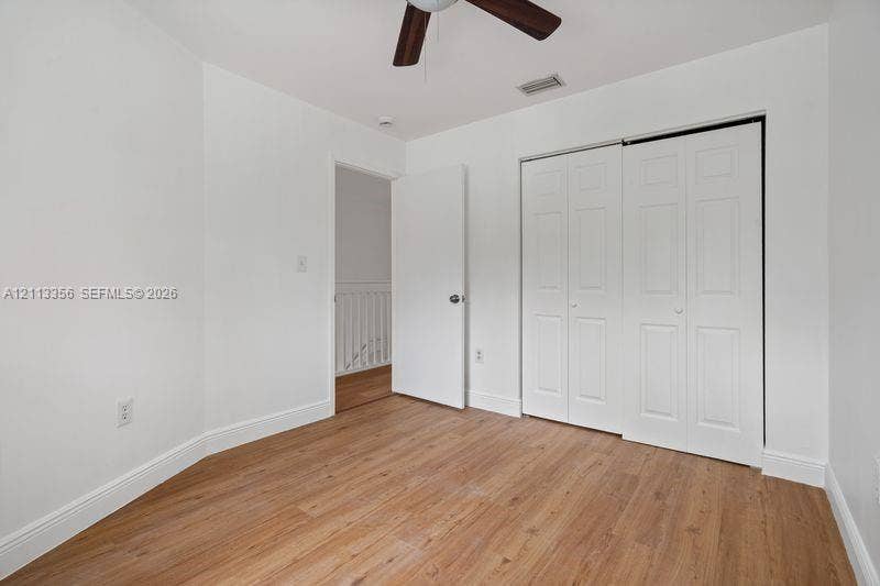 8715 SW 152nd Avenue, #312, Miami, Miami, FL 33193 Room featuring wood-finish flooring, a ceiling fan with integrated lighting, and a closet with white paneled bi-fold doors