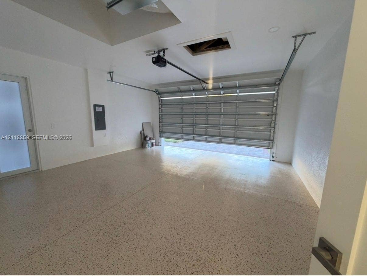 Multi-car garage featuring epoxy-coated flooring, recessed ceiling lighting, and a frosted glass entry door