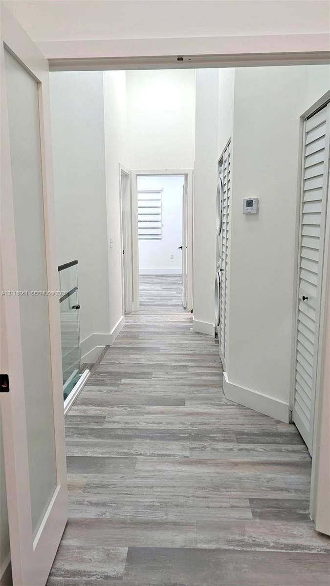 9395 Boca River Circle, Boca Raton, Boca Raton, FL 33434 Staircase featuring wood-finish treads, frameless glass railings with black hardware, and vertical slat accent wall paneling over large-format tile flooring