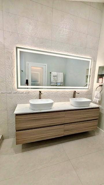 9395 Boca River Circle, Boca Raton, Boca Raton, FL 33434 Walk-in shower featuring a frameless glass enclosure, pebble-stone flooring, and textured wall tile, paired with a floating wood-finish vanity and illuminated mirror
