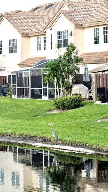 9395 Boca River Circle, Boca Raton, Boca Raton, FL 33434 Multi-story exterior featuring multi-pane windows, a shingled roof, screened-in patio, and direct water frontage on a lake
