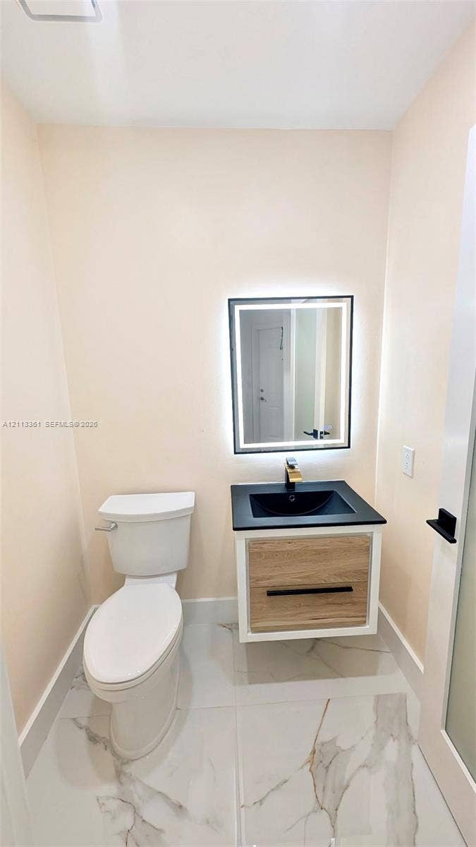 9395 Boca River Circle, Boca Raton, Boca Raton, FL 33434 Stacked laundry unit with white louvered bifold closet doors and wood-finish flooring