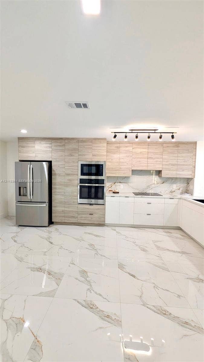 9395 Boca River Circle, Boca Raton, Boca Raton, FL 33434 Kitchen featuring white flat-panel cabinetry, light-toned wood-finish upper cabinets, large-format veined tile flooring, a stainless steel dishwasher, and a multi-light track fixture