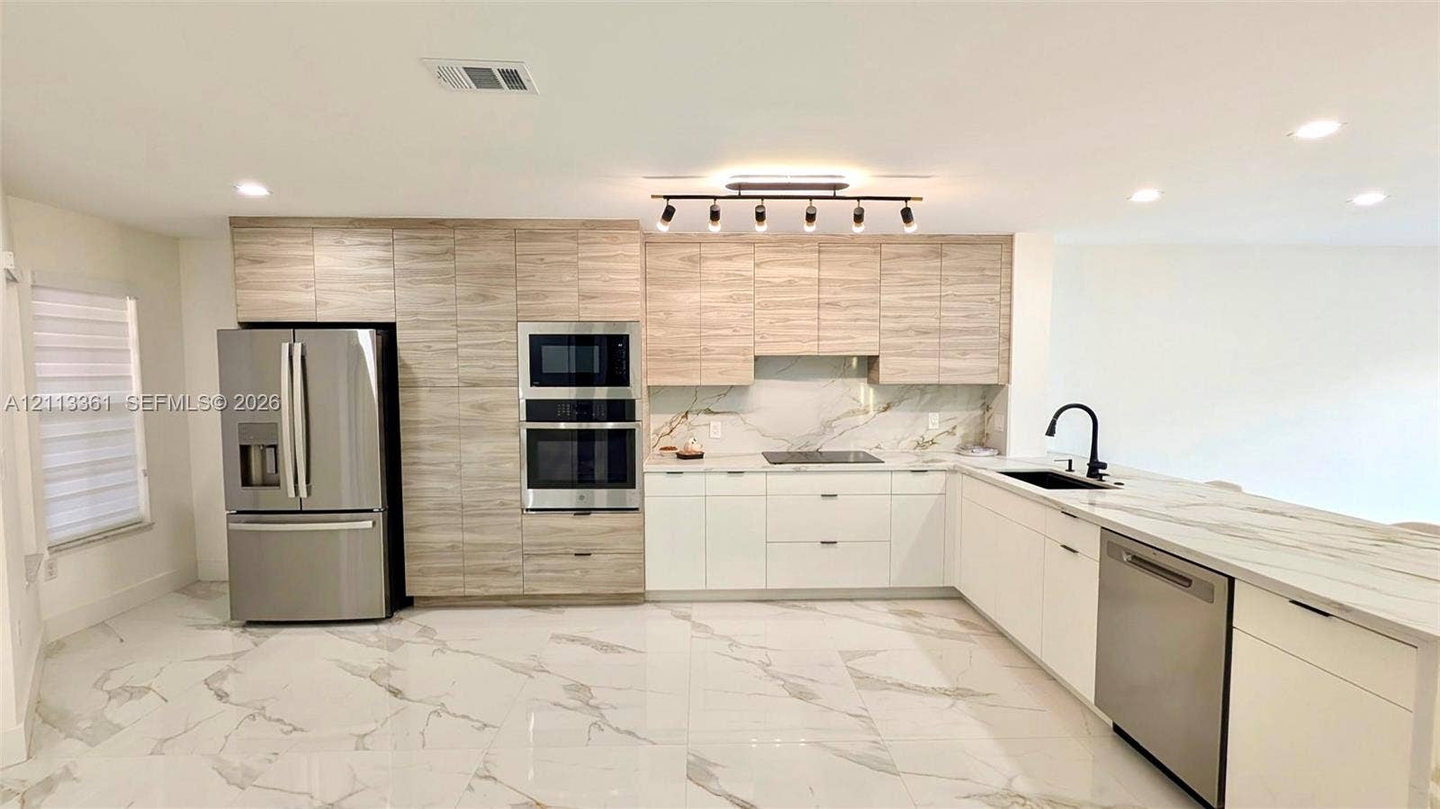 9395 Boca River Circle, Boca Raton, Boca Raton, FL 33434 Kitchen featuring two-tone cabinetry with wood-finish upper cabinets, white lower cabinetry, integrated stainless steel appliances, stone-finish tile flooring, and multi-bulb track lighting