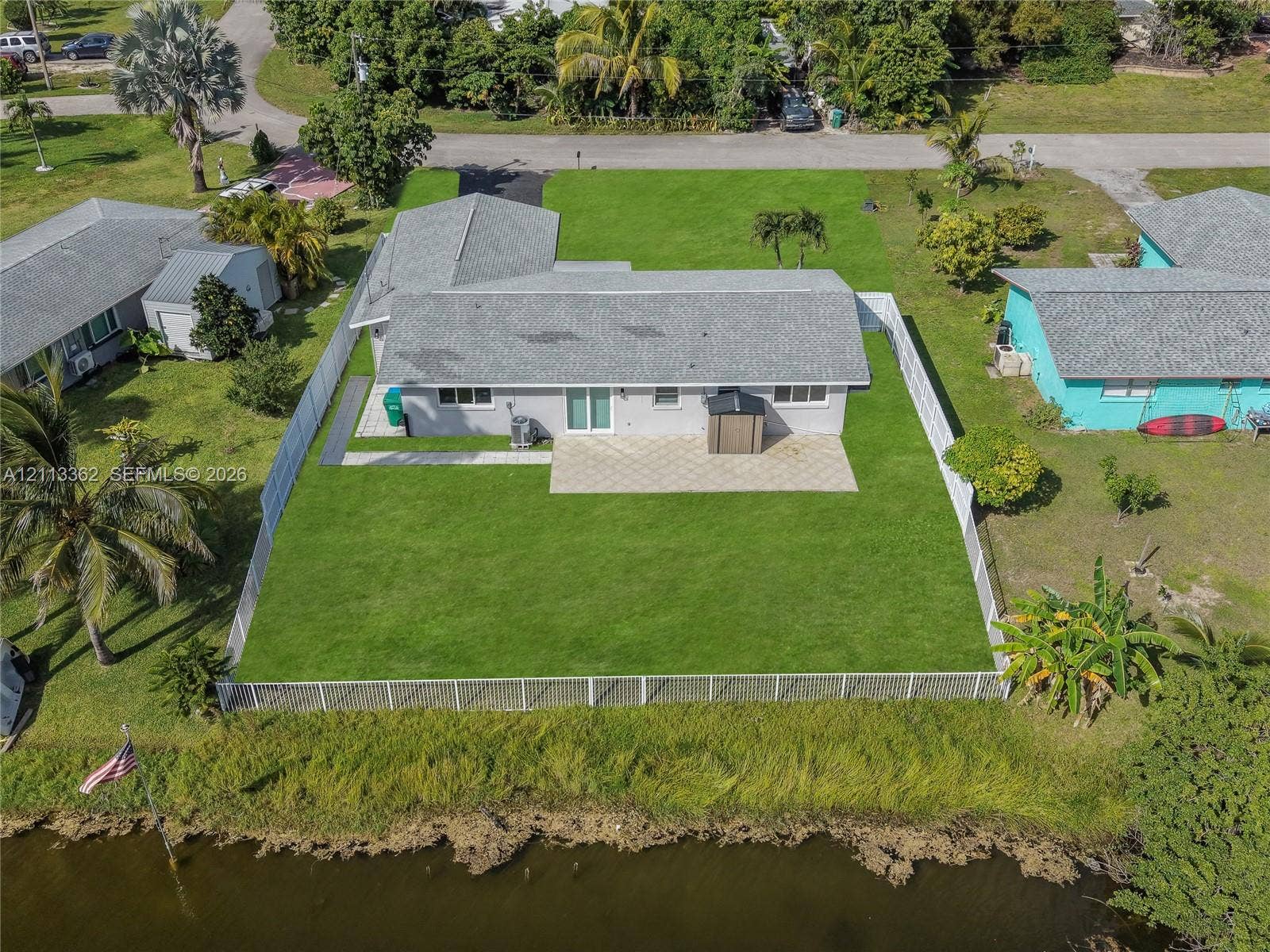 1206 NE 4th Terrace, Cape Coral, FL 33909 Waterfront property featuring a fenced backyard, paved patio, and grass lawn