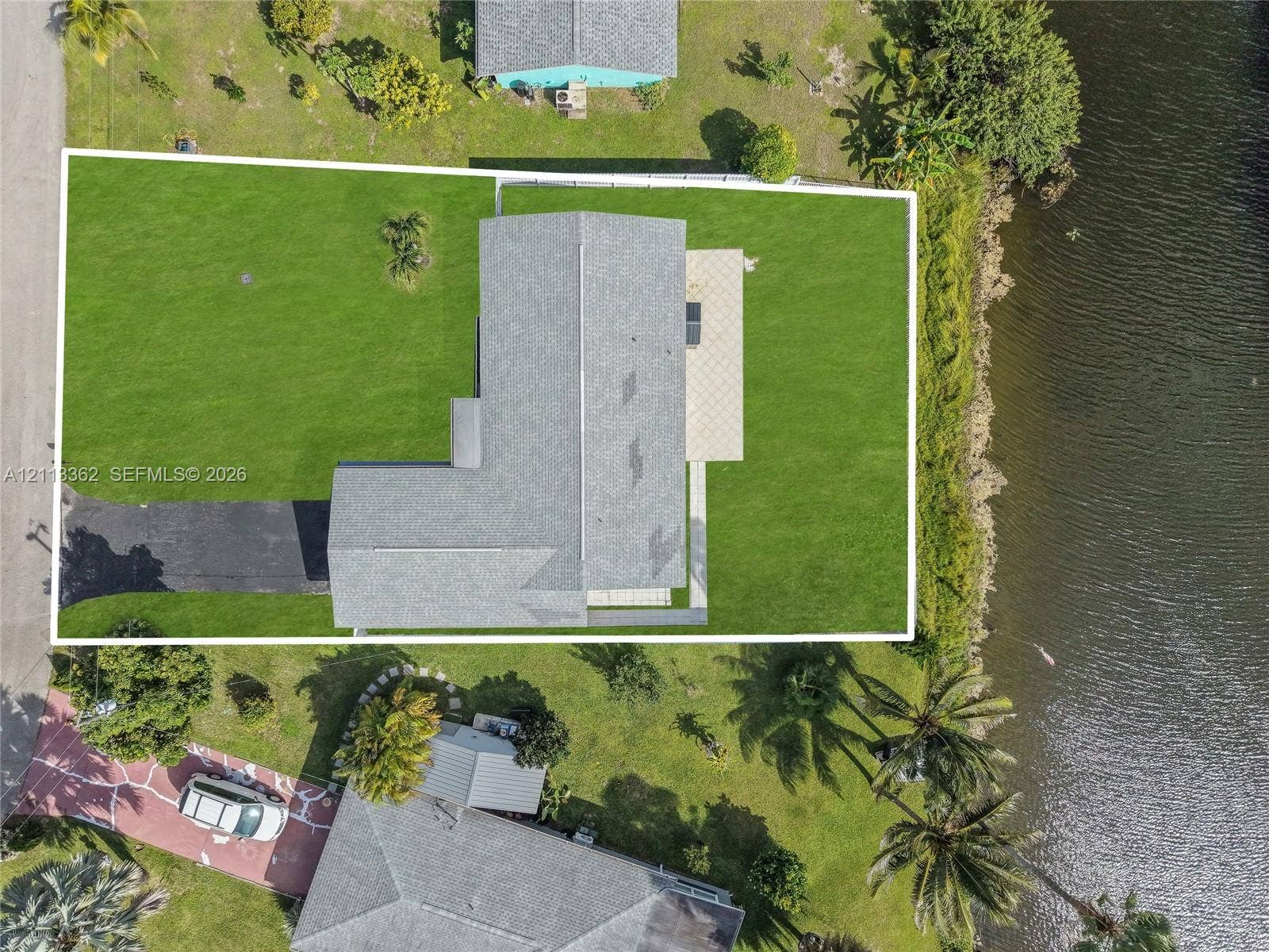 1206 NE 4th Terrace, Cape Coral, FL 33909 Aerial perspective featuring a waterfront lot, asphalt driveway, asphalt shingle roofing, and paved patio area