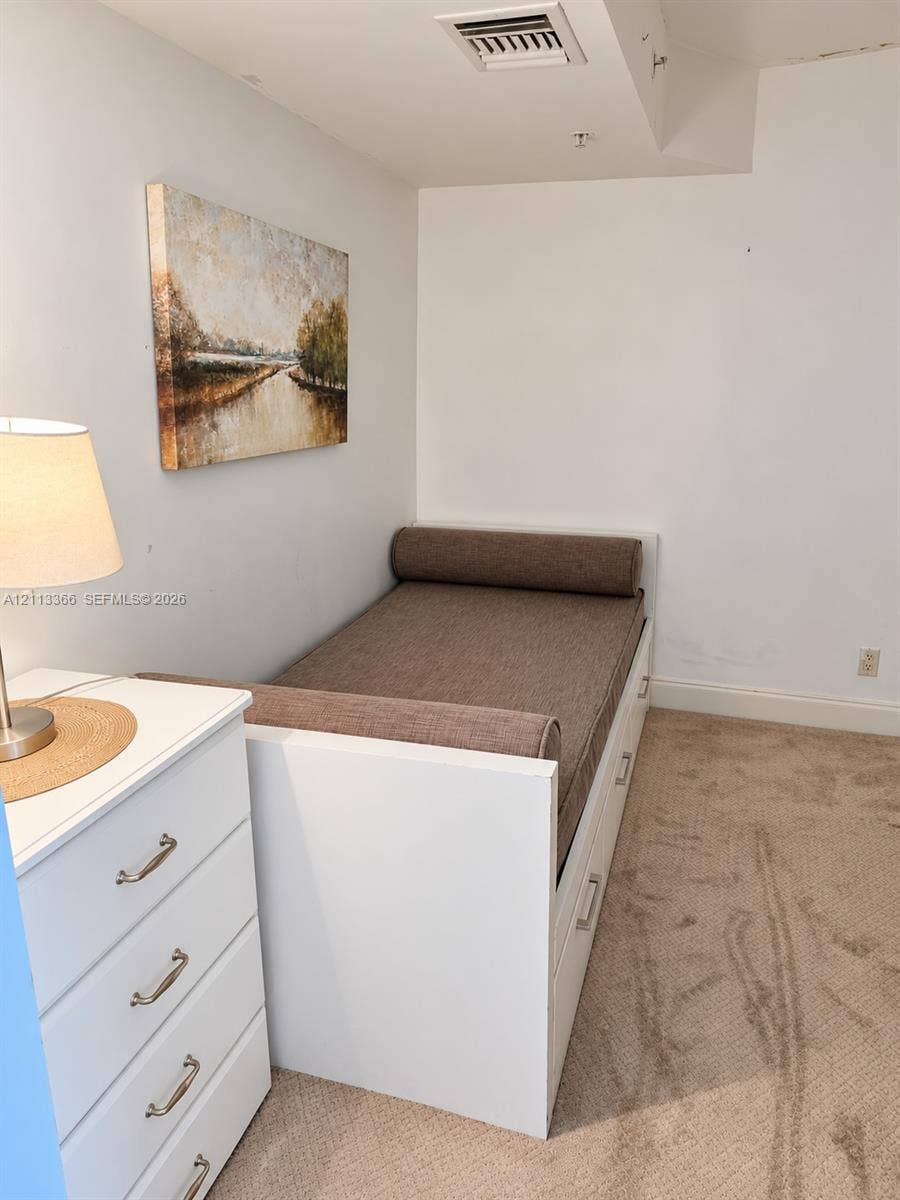9499 Collins Avenue, #904, Surfside, FL 33154 Built-in white platform bed frame featuring integrated under-bed storage drawers and neutral wall-to-wall carpeting