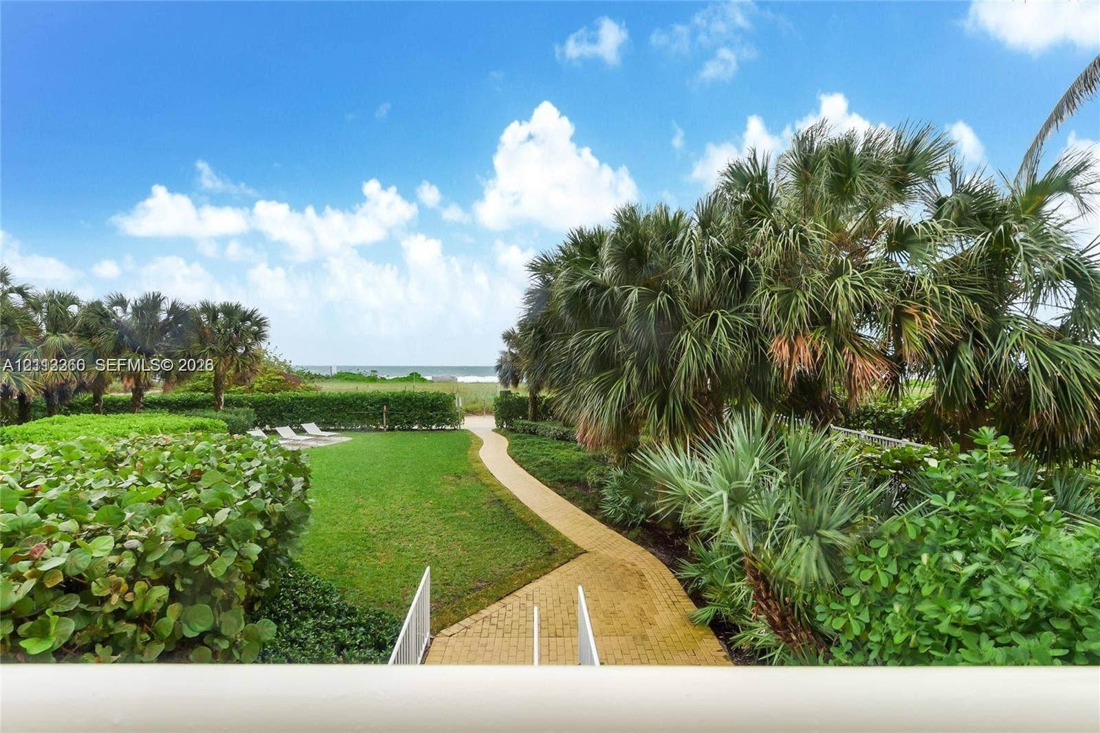 9499 Collins Avenue, #904, Surfside, FL 33154 Expansive grounds featuring a manicured lawn, paver walkway, mature palm trees, and dense perimeter landscaping