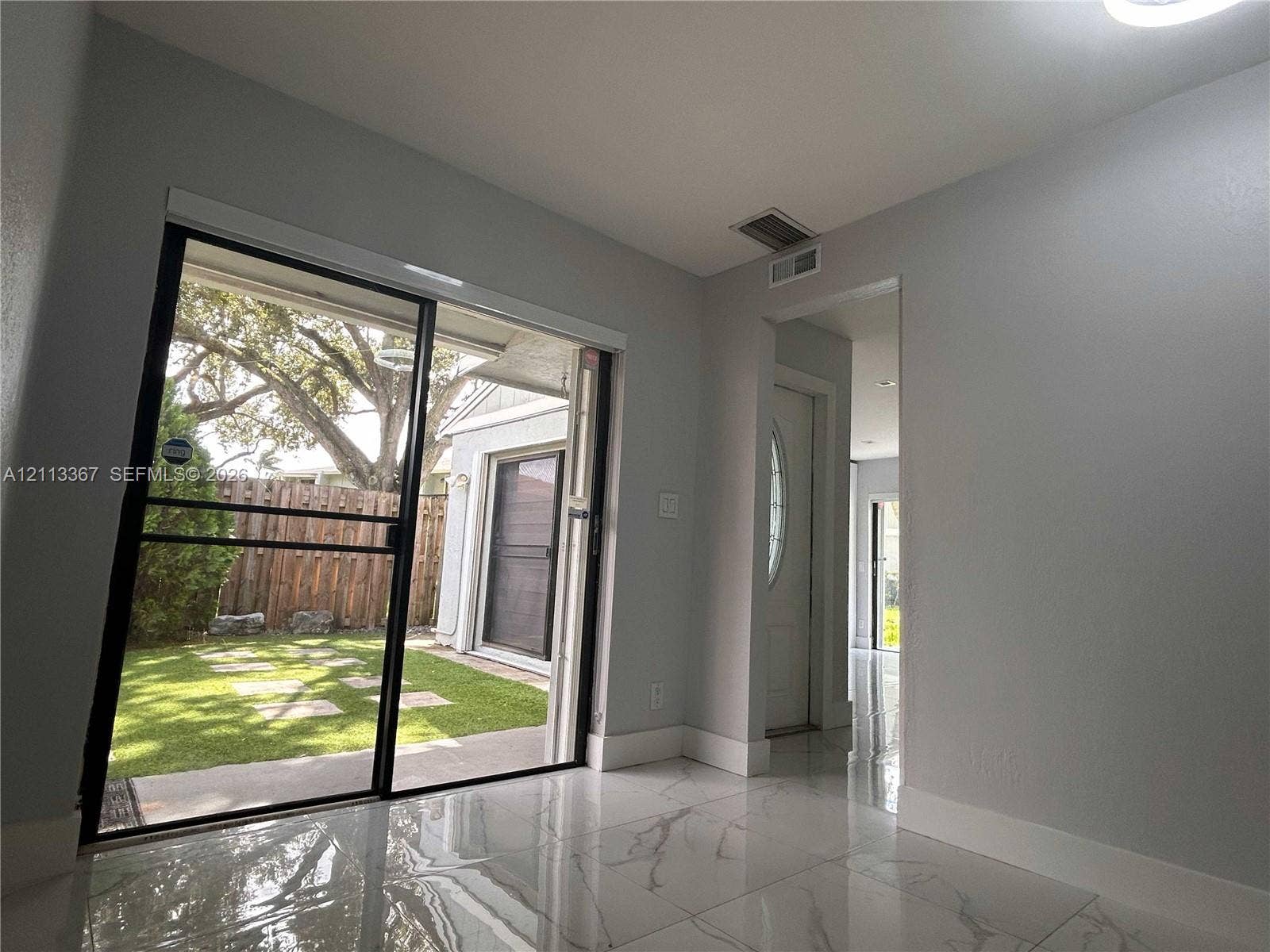 Large format rectified tile flooring, black-framed sliding glass door, and exterior yard with stone pavers
