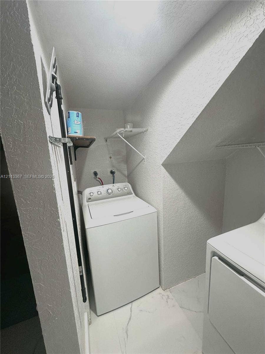 Laundry area featuring stone-finish flooring and built-in wire shelving