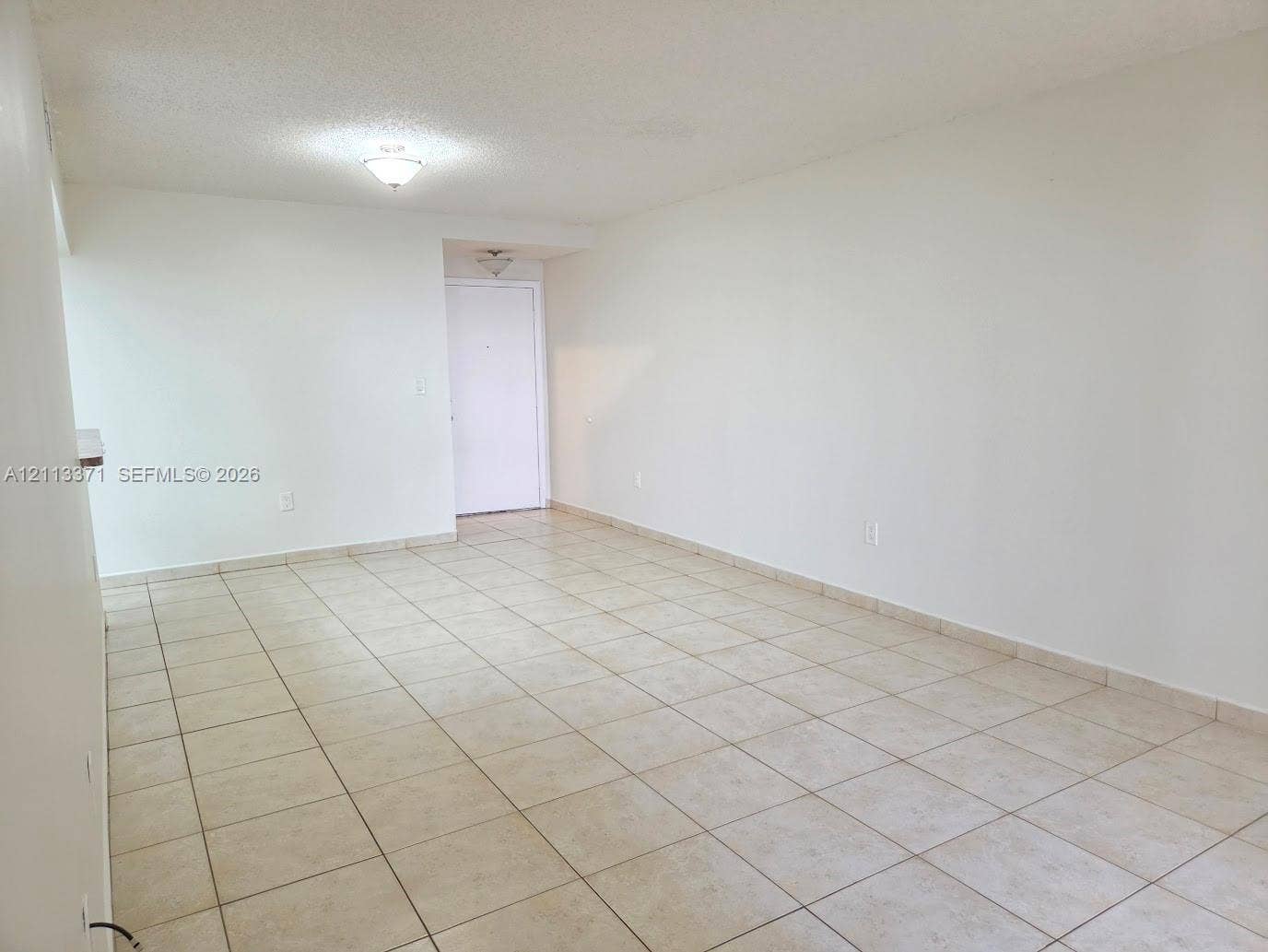 9439 Fontainebleau Boulevard, #104, Miami, Miami, FL 33172 Open interior space featuring light-toned tile flooring, neutral wall paint, and two flush-mount ceiling light fixtures