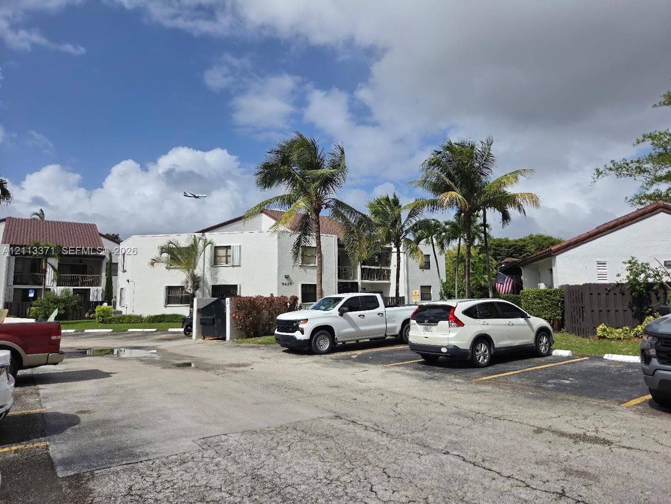 9439 Fontainebleau Boulevard, #104, Miami, Miami, FL 33172 Multi-story residential building featuring white stucco exterior, tile roofing, balcony railings, and mature palm trees