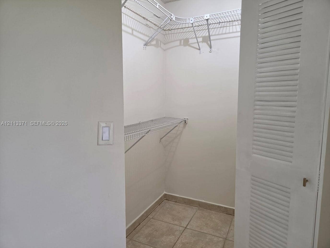 9439 Fontainebleau Boulevard, #104, Miami, Miami, FL 33172 Walk-in closet featuring white louvered doors, tile flooring, and installed wire shelving
